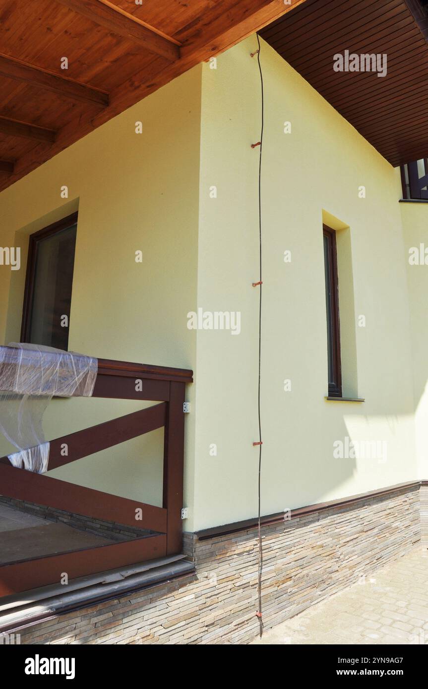 Protezione contro i fulmini residenziali. Primo piano a terra di una casa con un'asta di illuminazione, un'asta di messa a terra, un limitatore di sovratensione, un soppressore di sovratensioni per i dispositivi di protezione dai fulmini Foto Stock