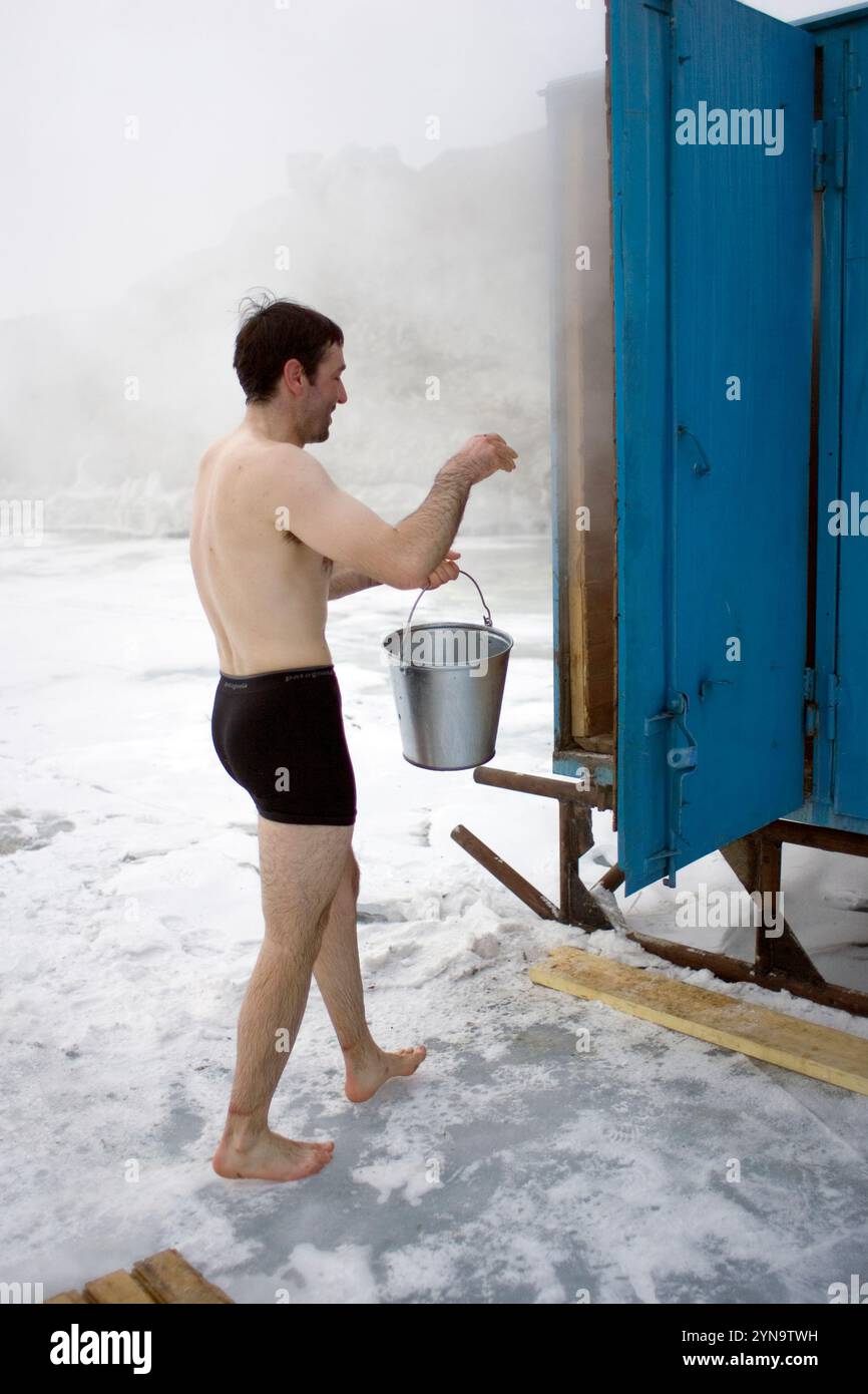 Un uomo entra in un bagno turco di legno sul lago ghiacciato Baikal nell'isola di Olkhon, Siberia, Russia. Foto Stock