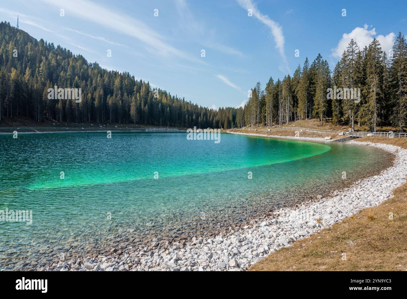 Un bellissimo lago artificiale circondato da una pineta in una giornata di sole, il lago Montagnoli, le Alpi, l'Italia Foto Stock