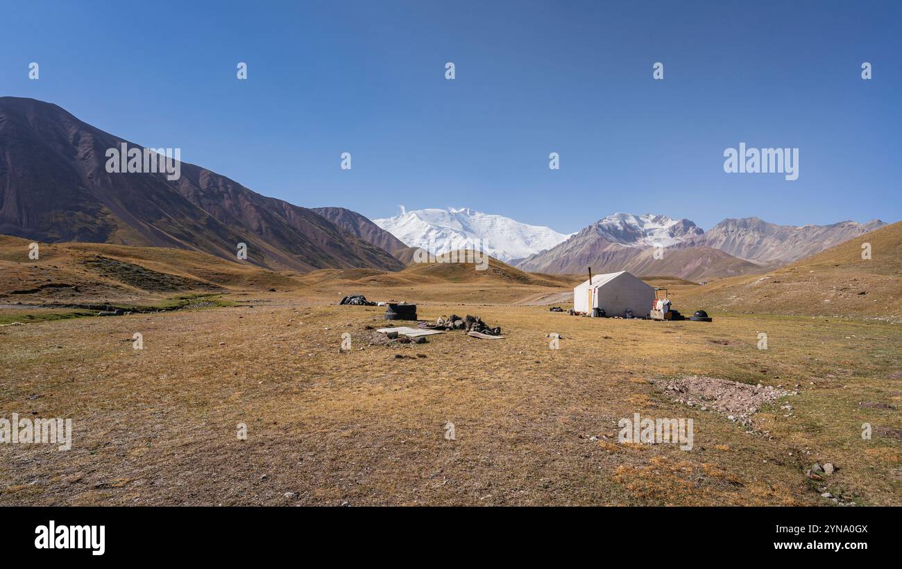 Vista panoramica del pascolo estivo d'alta quota e della tenda della casa nella valle dell'Alai con il picco Lenin sullo sfondo, Sary Mogul, Kirghizistan Foto Stock