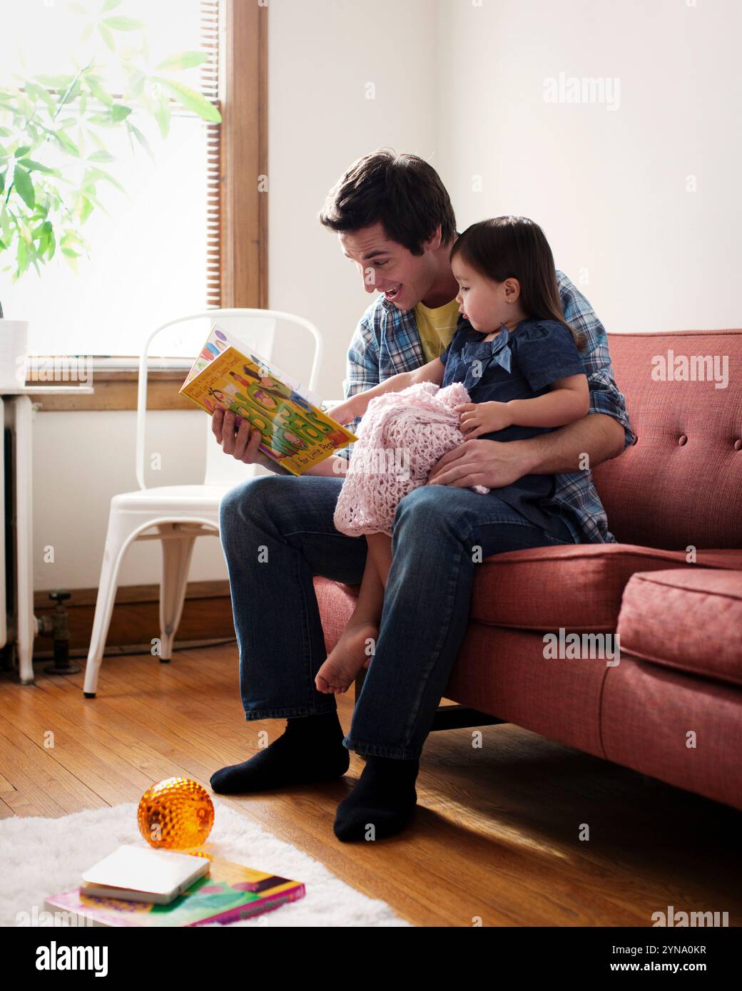 Un padre legge un libro per bambini a sua figlia sul divano, il 30 gennaio 2011. Foto Stock