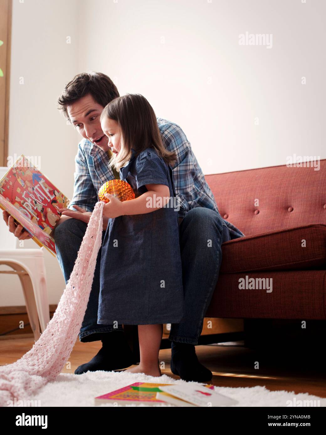 Un padre legge un libro per bambini a sua figlia sul divano, il 30 gennaio 2011. Foto Stock