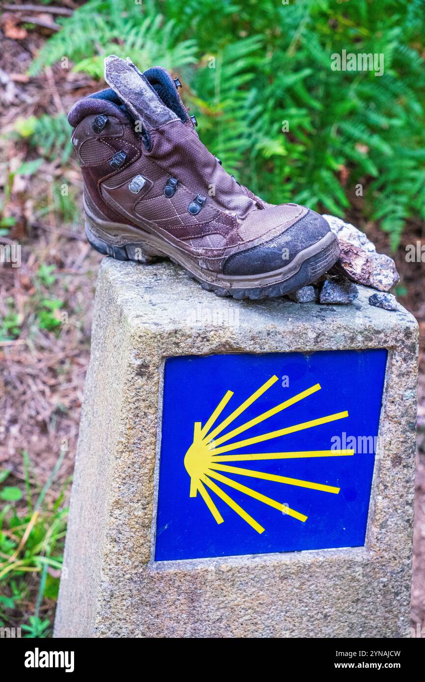 Spagna, Galizia, dintorni di Caldas de Reis, segno della via portoghese verso Santiago de Compostela, scarpa da trekking lasciata da un pellegrino Foto Stock