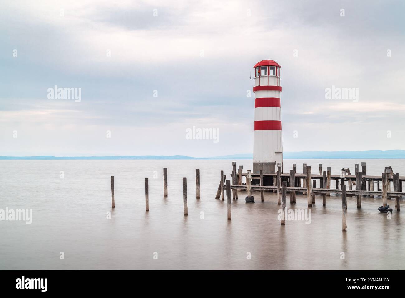 PODERSDORF AM SEE, AUSTRIA - 7 APRILE 2023: Faro con molo in legno sul lago. Foto Stock