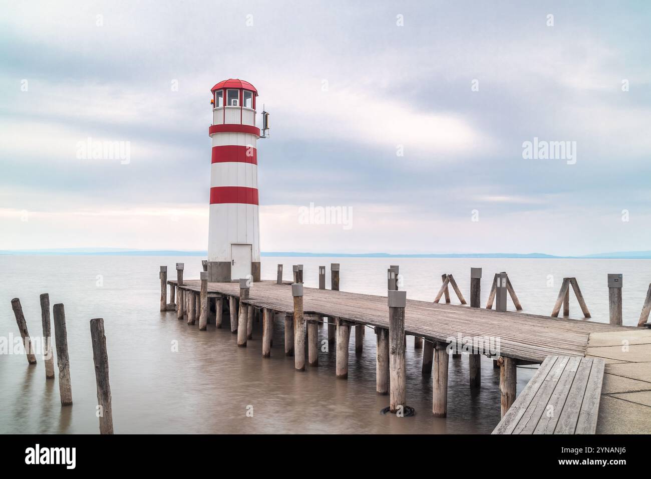 PODERSDORF AM SEE, AUSTRIA - 7 APRILE 2023: Faro con molo in legno sul lago. Foto Stock