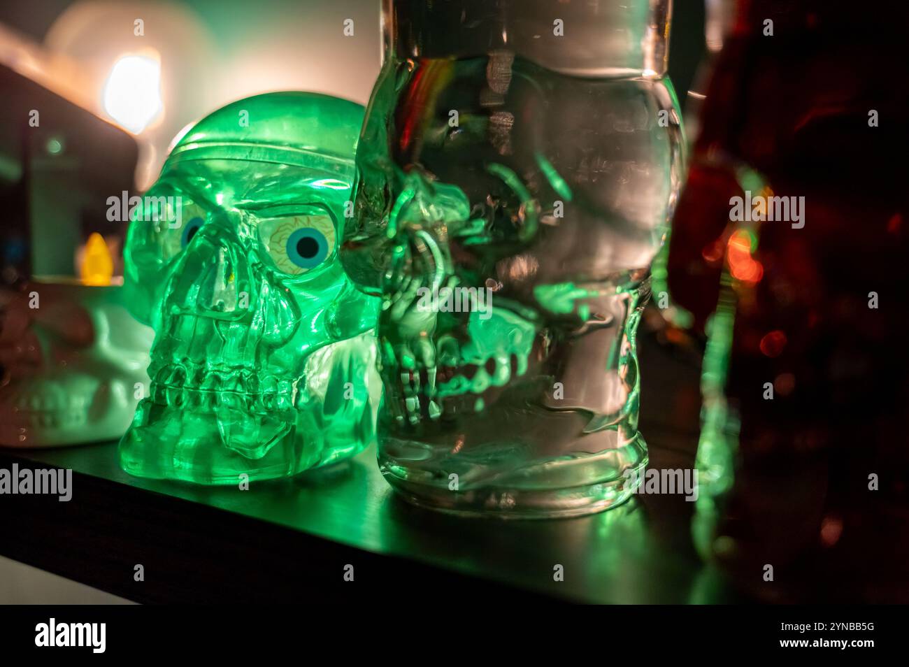 Lanterna a forma di teschio e bottiglia esposte sullo scaffale come decorazione di Halloween. Configurazione spettrale ma elegante per un'atmosfera festosa Foto Stock