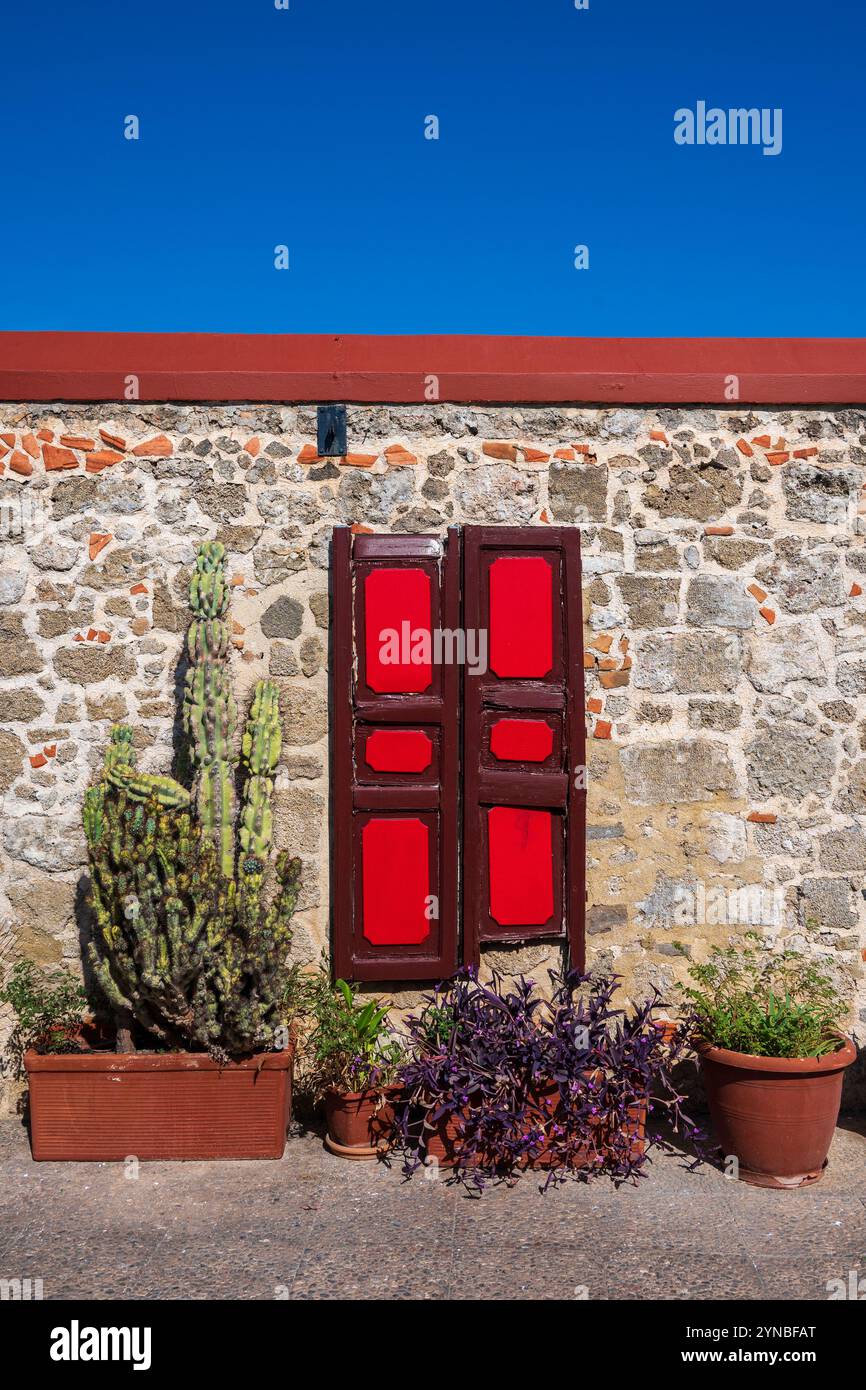 Vivaci persiane in legno dipinte di rosso montate su un muro di pietra tradizionale a Rodi Foto Stock