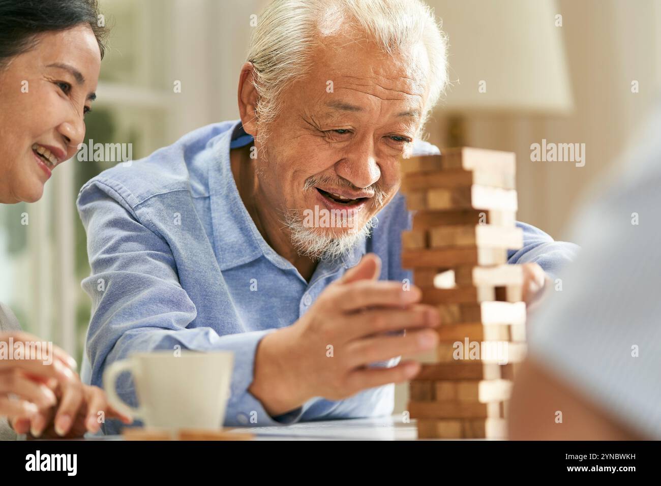 gruppo di giovani asiatici felici che si riuniscono a casa giocando insieme a elementi di base Foto Stock