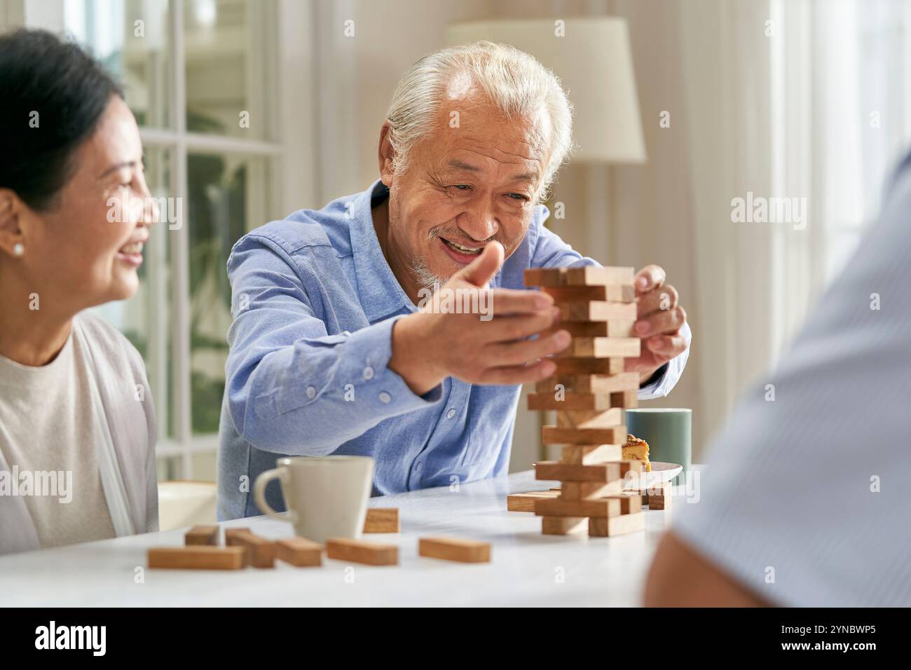 gruppo di giovani asiatici felici che si riuniscono a casa giocando insieme a elementi di base Foto Stock
