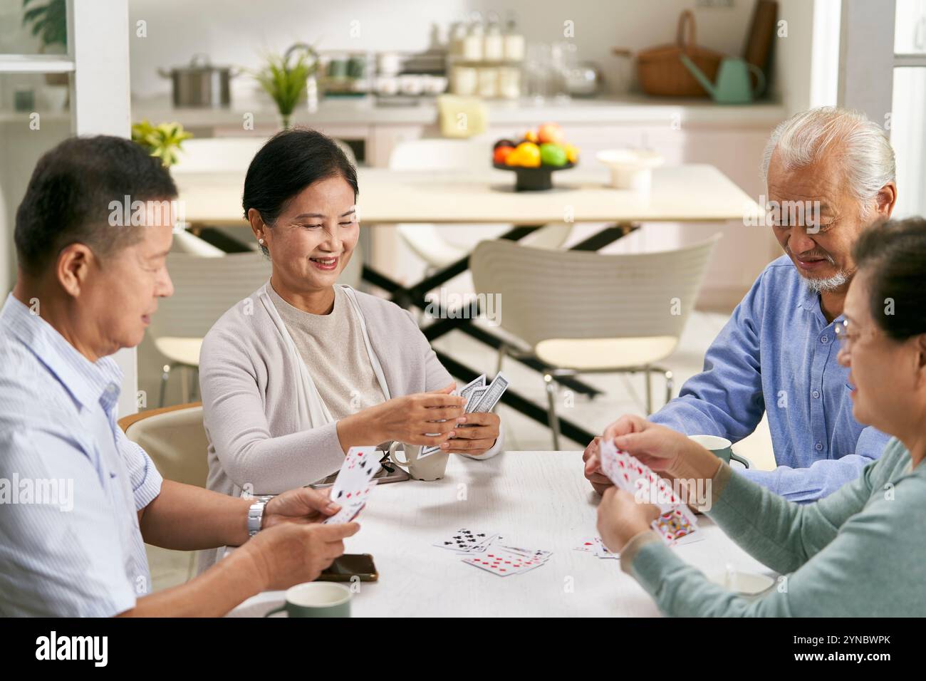 gruppo di giovani asiatici felici due coppie che si riuniscono a casa giocando a carte insieme Foto Stock