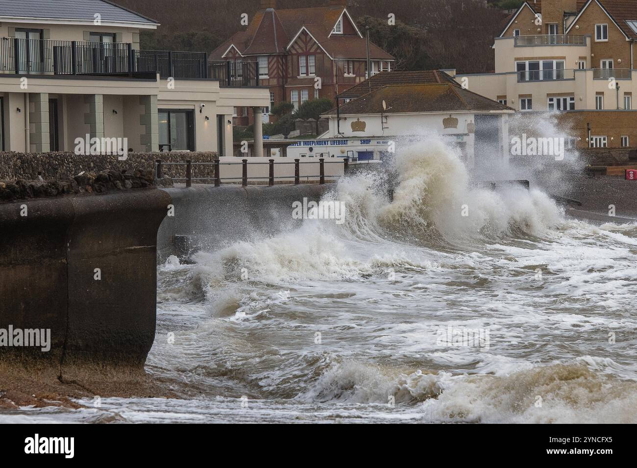 Grandi onde che colpiscono un muro costiero sull'isola di wight a Freshwater Bay durante una tempesta invernale, onde che si infrangono sul muro del mare e sugli edifici sulla IOW Foto Stock