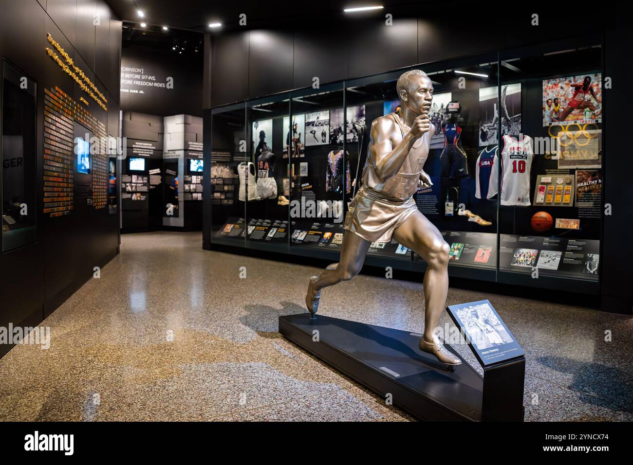 WASHINGTON DC, Stati Uniti — Una statua di Jesse Owens in pieno ritmo commemora il suo storico successo nel vincere quattro medaglie d'oro alle Olimpiadi del 1936, esposta nella mostra Sports: Leading the Playing Field presso il National Museum of African American History and Culture. La mostra esplora l'intersezione tra atletica e attivismo nella storia afroamericana. Foto Stock