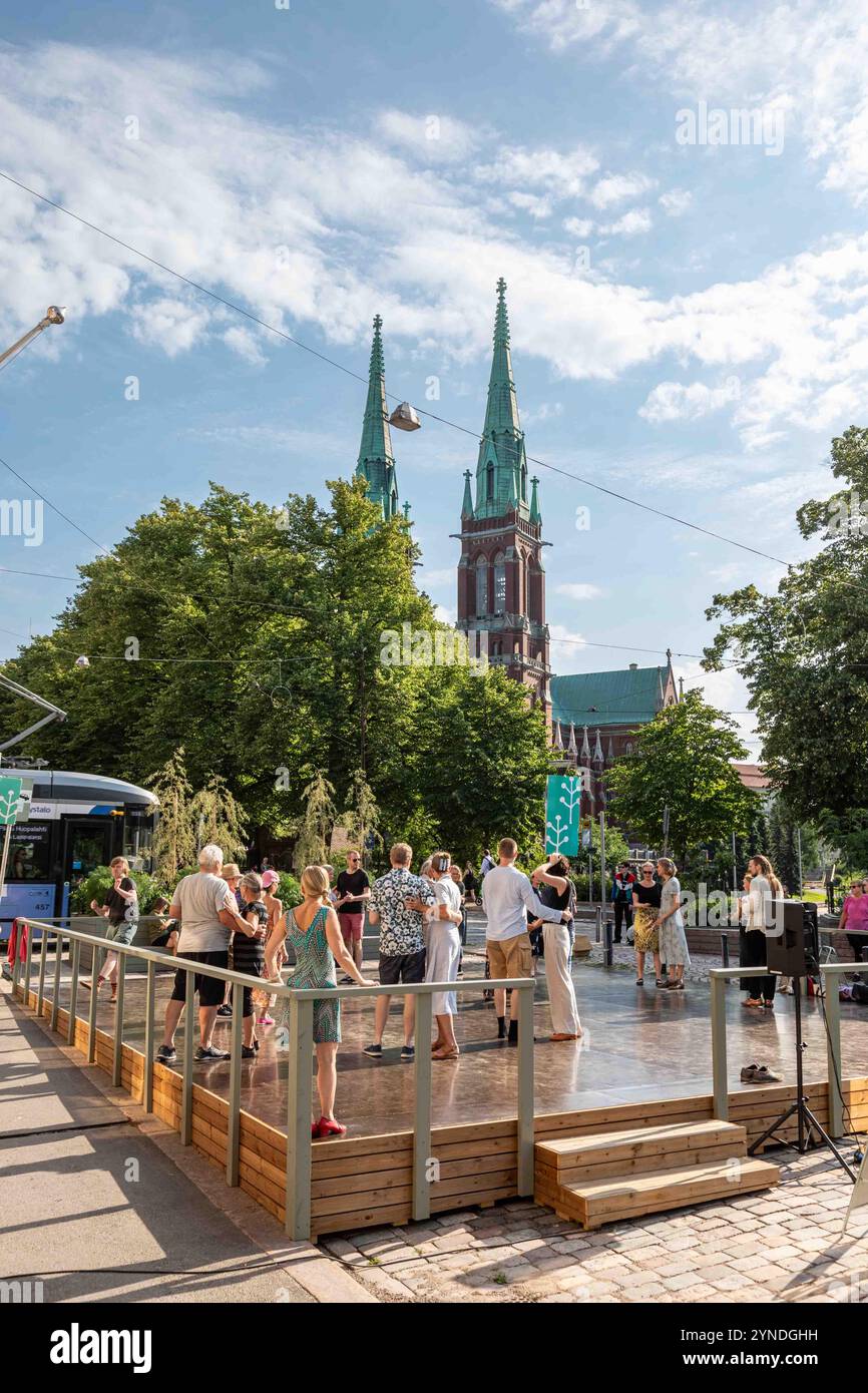 Persone che ballano nelle strade estive si esibiscono in un palco di eventi nella Piazza del Museo del Design nel quartiere Ullanlinna di Helsinki, Finlandia Foto Stock