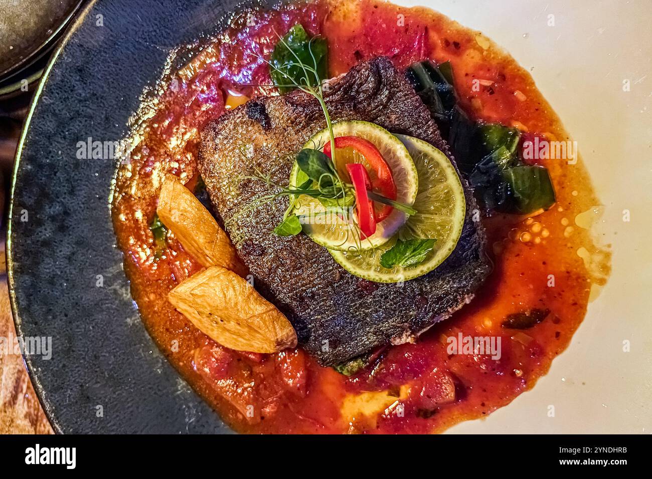 Un filetto di pesce grigliato in salsa di pomodoro con lime e peperoncino, servito al Restaurant De Heeren a Pietermaai, Willemstad, Curaçao. Pietermaai era una volta un quartiere decadente. Negli ultimi anni è diventato il centro gastronomico della capitale, uno dei suoi quartieri storici più recentemente rinnovati. Foto Stock