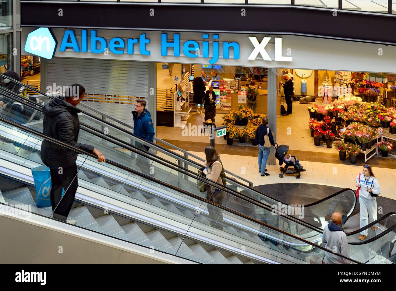 Facciata del supermercato Albert Heijn XL all'interno del centro commerciale Diemen, vicino ad Amsterdam. Gli acquirenti sulle scale mobili, una che porta un sacchetto di plastica blu del marchio Foto Stock