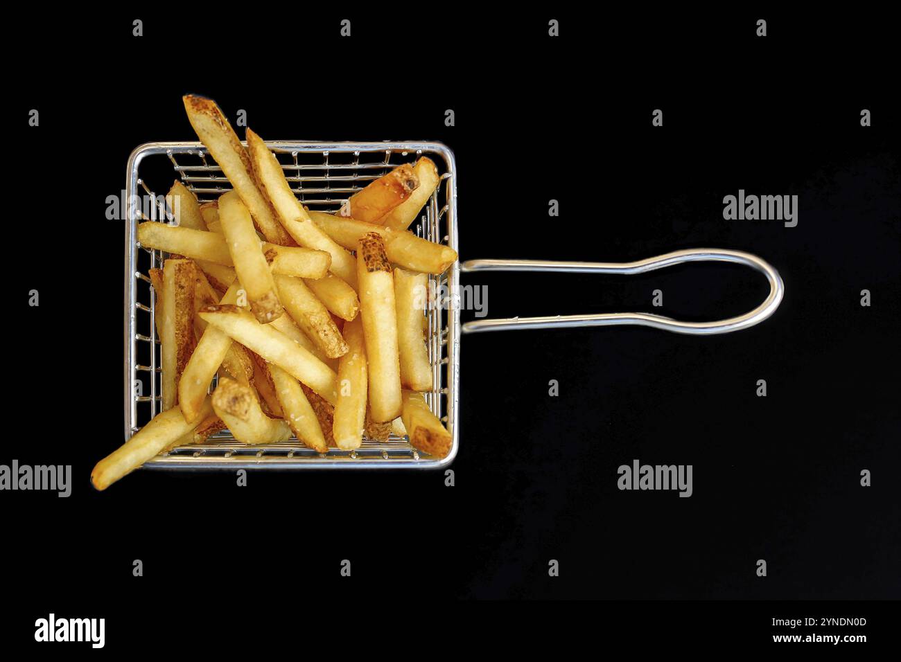 Una prospettiva aerea di un modesto cestino contenente patatine fritte, adagiato su uno sfondo scuro Foto Stock