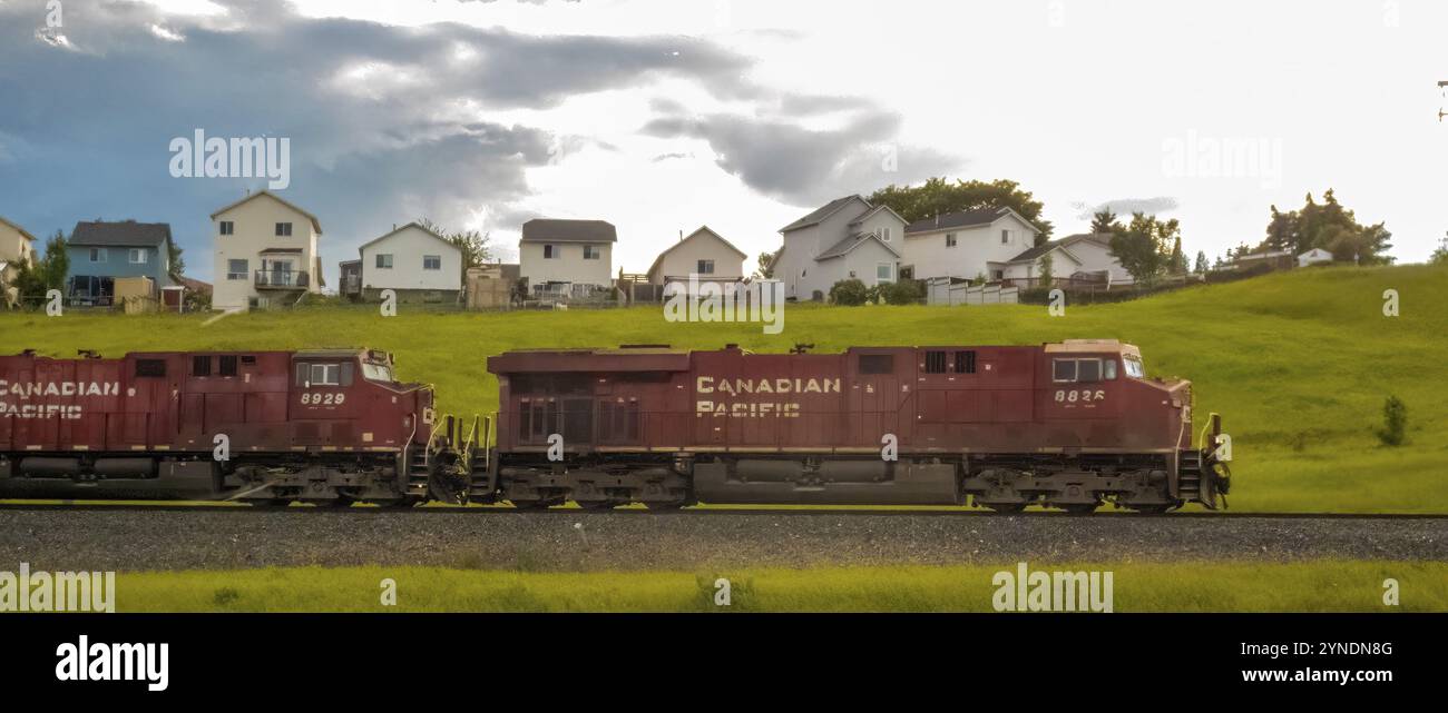 Calgary, Alberta, Canada. 2 agosto 2024. Un treno della Canadian Pacific Railway passa attraverso un paesaggio suburbano, con case residenziali visibili nel bac Foto Stock