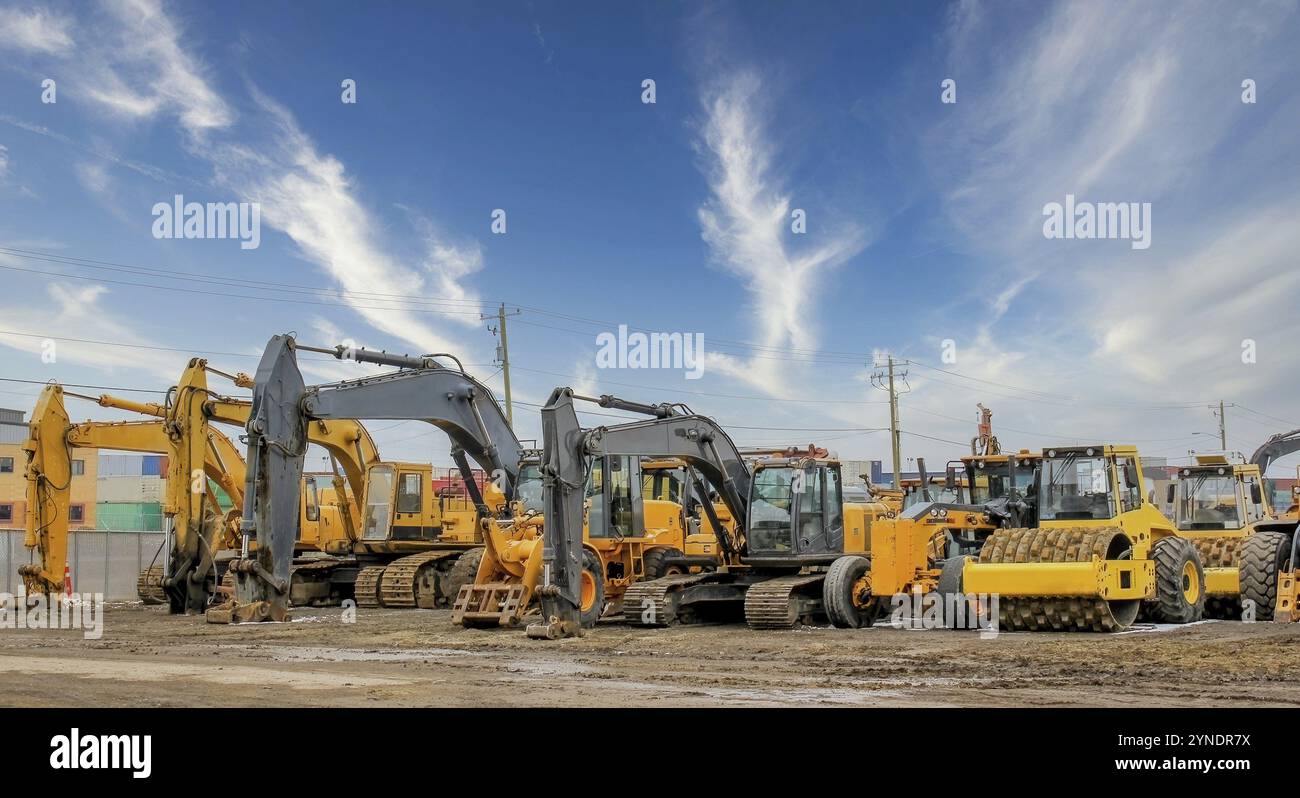 Vari veicoli per l'edilizia pesante, come escavatori, scavatori, macchine per la movimentazione del terreno e bulldozer, sono stazionati in un cantiere per tutta la durata della vittoria Foto Stock