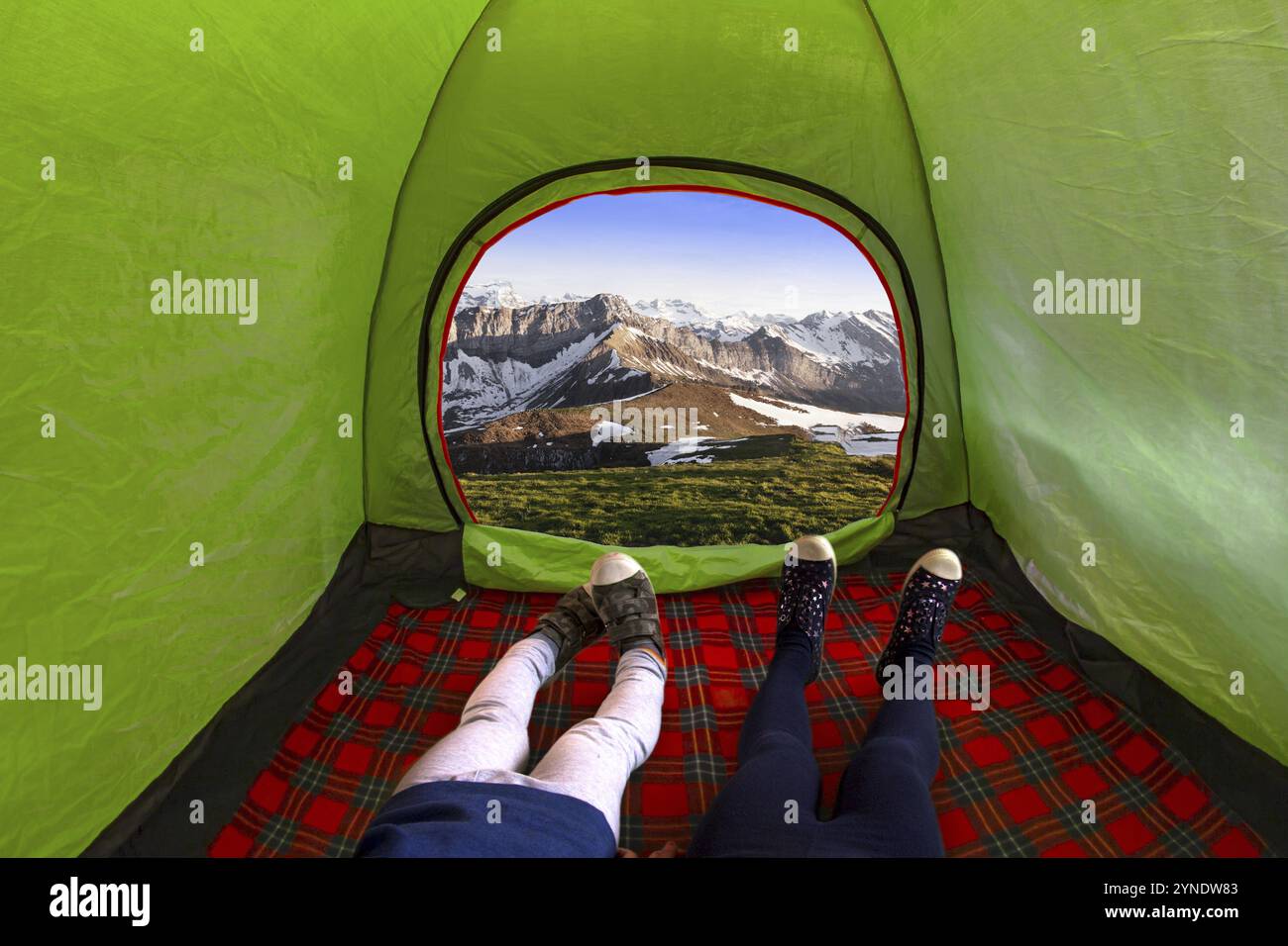 Due bambini all'interno su una tenda da campeggio che guarda montagne durante il giorno Foto Stock