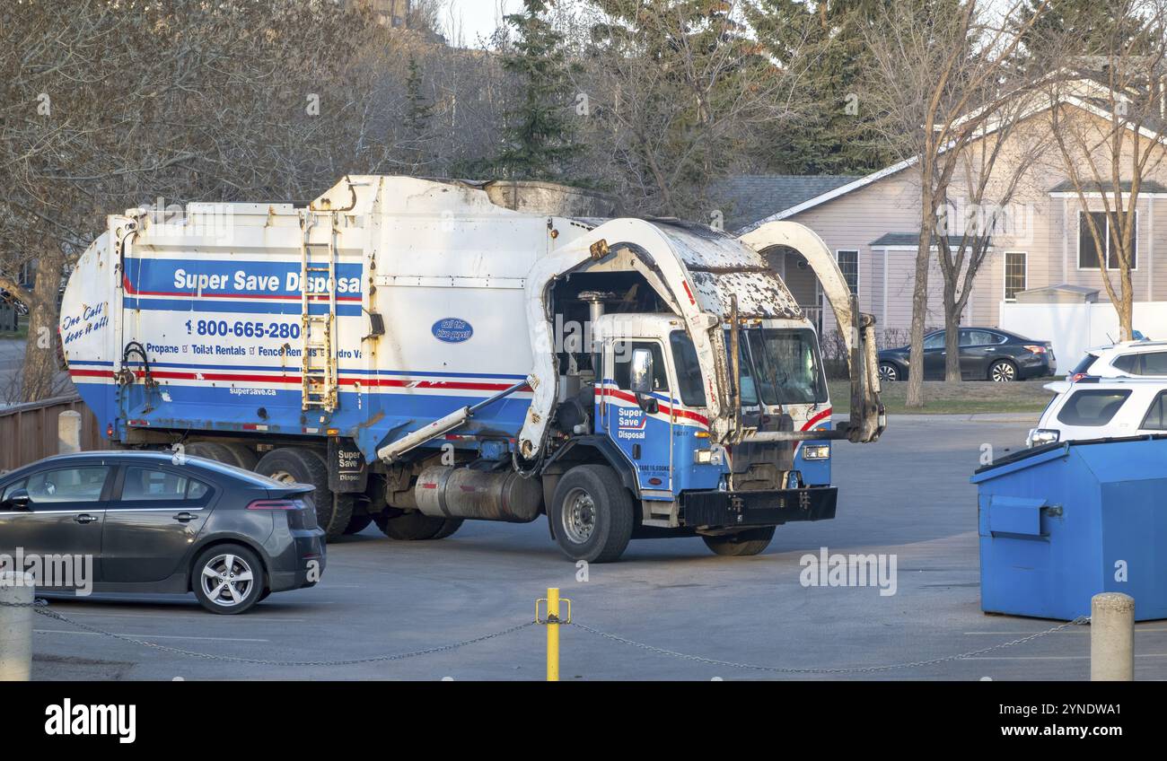 Calgary, Alberta, Canada. 2 maggio 2023. Un camion dei rifiuti per rifiuti e riciclaggio, in procinto di caricare un grande bidone dei rifiuti blu metallico. Concetto: Smaltimento dei rifiuti Foto Stock
