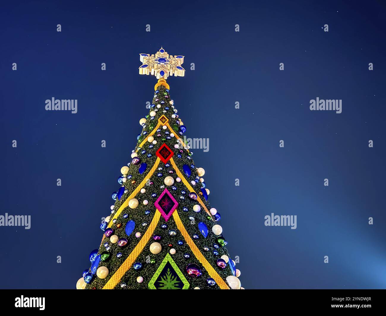 Vista orizzontale di un albero di Natale che si illumina di vari colori durante la notte Foto Stock