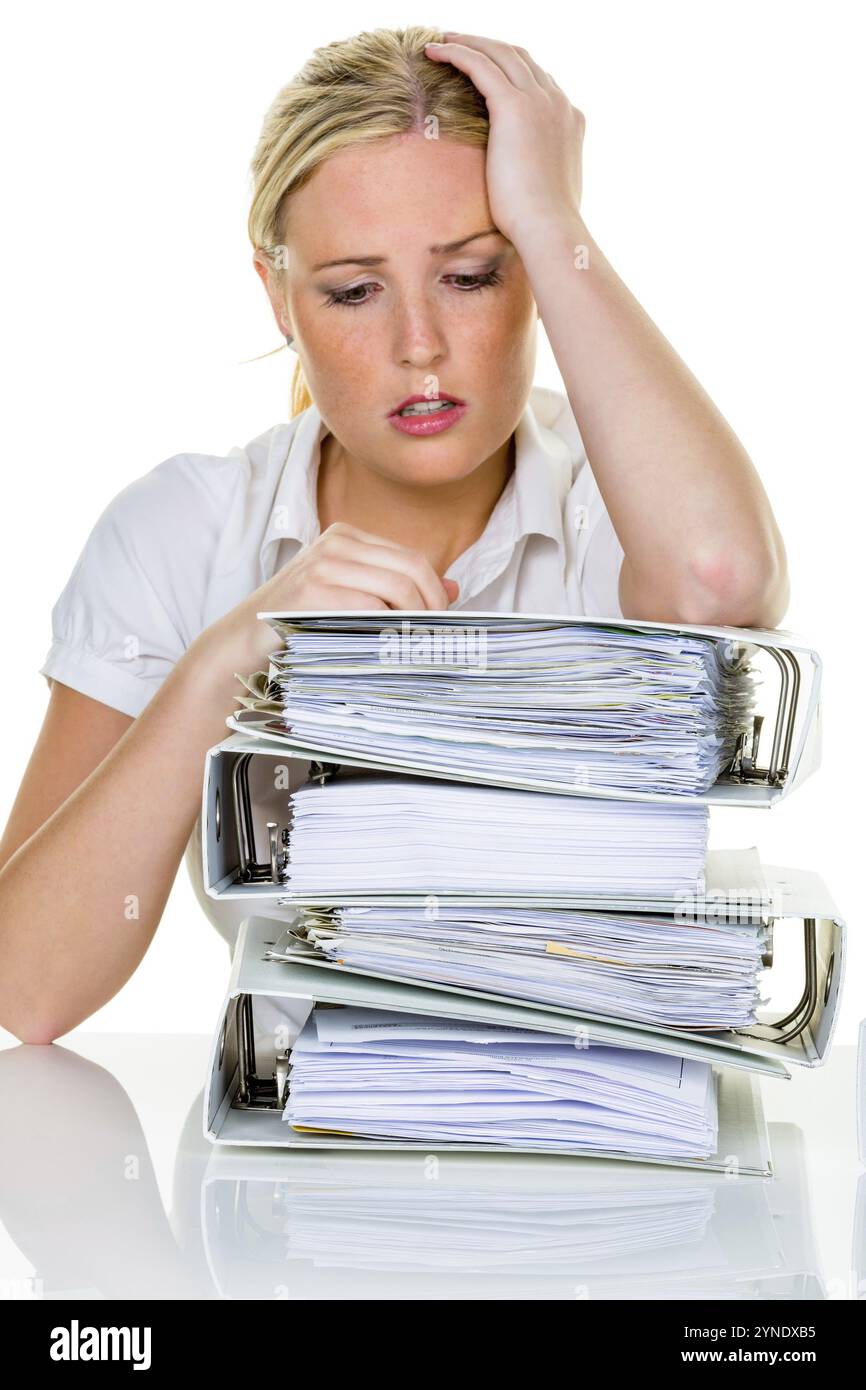 Una donna bionda in ufficio è travolta dal lavoro. Sindrome di burnout al lavoro o studio, mucchio di fascicoli, segretaria, overworked, overstressed Studio sh Foto Stock