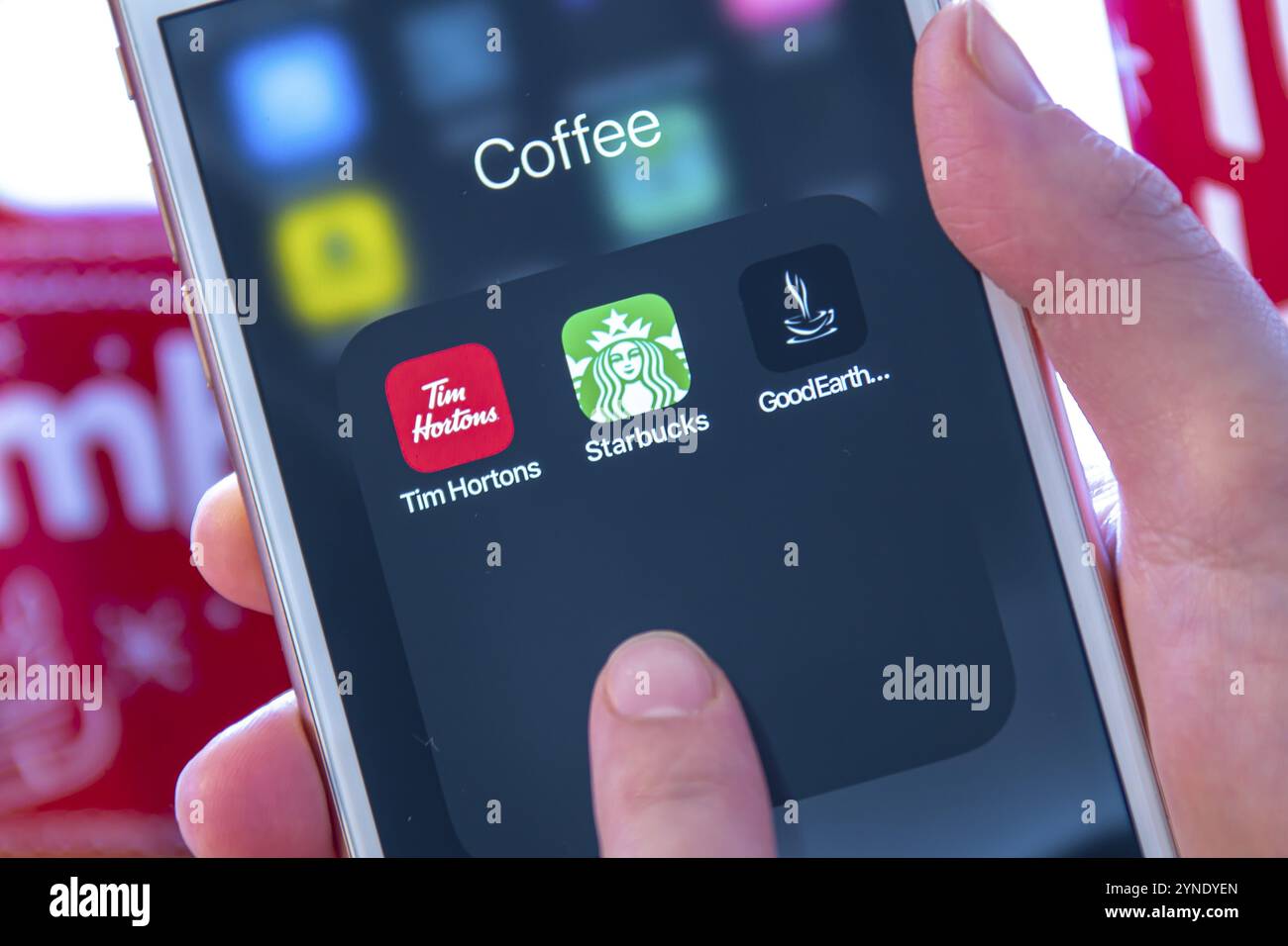 Calgary, Alberta. Canada dicembre 28 2019. Una persona che ha in mano un iPhone con app per caffè di Tim Hortons, Starbucks e Good Earth Foto Stock