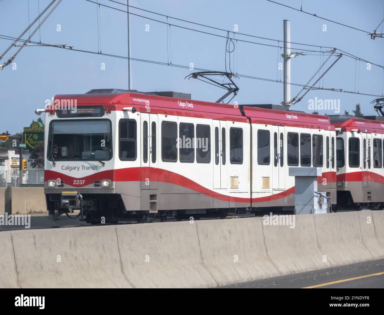 Calgary, Alberta, Canada. 21 luglio 2024. Un treno C di Calgary colorato in rosso e bianco viaggia lungo una corsia sopraelevata separata da un controbattitore Foto Stock