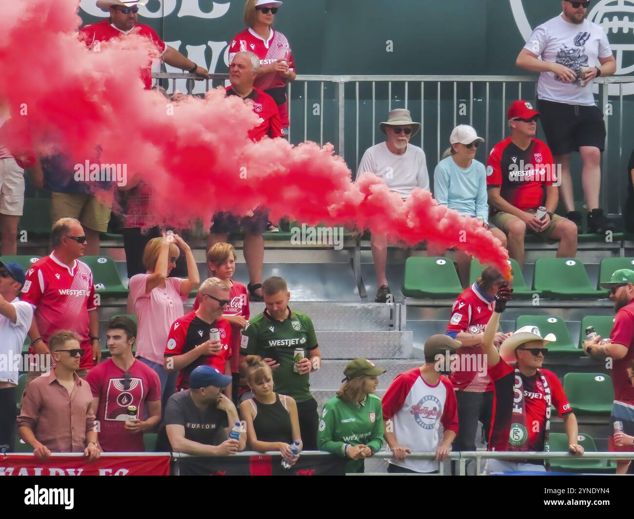 Calgary, Alberta, Canada. 17 luglio 2023. Un tifoso di football che regge una bomba fumé colorata durante una partita. Concetto: Passione per i tifosi, affollamento agli eventi sportivi Foto Stock