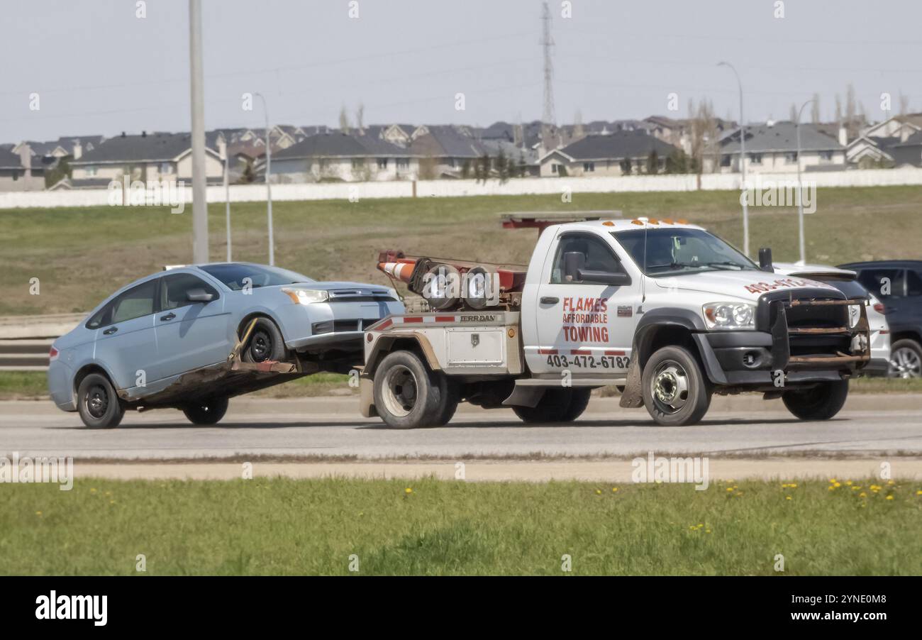 Calgary, Alberta, Canada. 10 maggio 2024. Un camion che trasporta un'auto rotta sulla strada Foto Stock