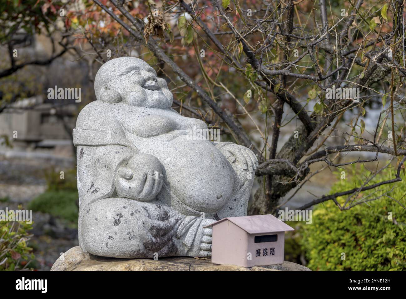 Nagahama, Prefettura di Shiga, Giappone. 21 novembre 2023. Una statua di pietra di Buddha sorridente in un santuario shintoista giapponese Foto Stock