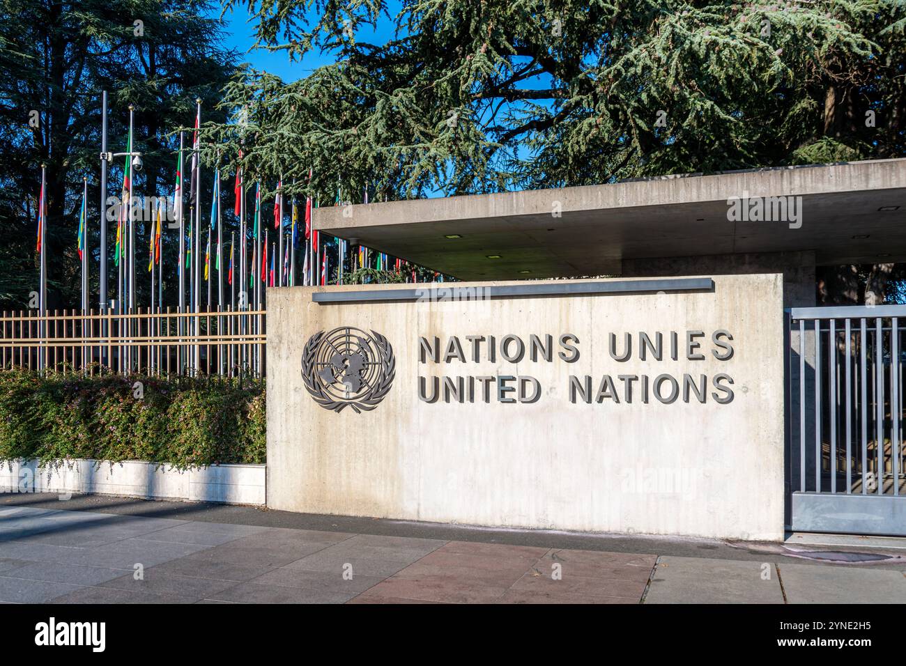Cartello e logo delle Nazioni Unite di fronte al Vicolo delle Bandiere all'ingresso del Palazzo delle Nazioni Unite, che ospita l'Ufficio delle Nazioni Unite a Ginevra Foto Stock