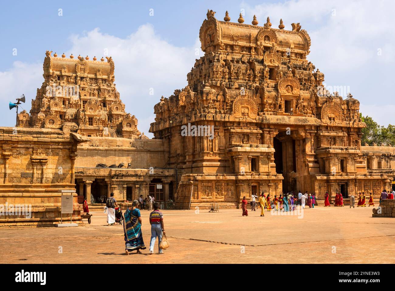 Devoti nella spaziosa prakara di Tanjai Periya Koil, fiancheggiata da due torreggianti gopuram sotto un cielo luminoso e soleggiato. Un assaggio sereno della spalla di Tamil Nadu Foto Stock