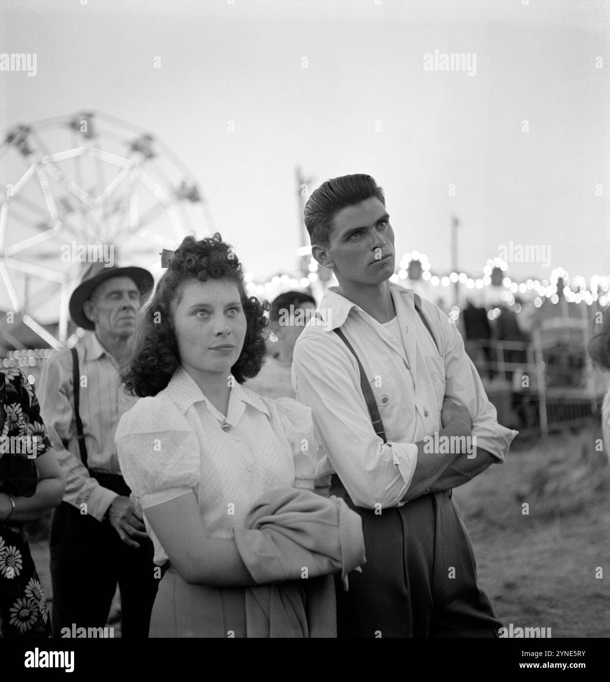 1942 , luglio , Klamath Falls , OREGON, USA : Dall' informazione originale: »Al sideshow del circo» . Foto di RUSSELL LEE ( 1903 - 1986 ), dipendente della United States Agricolture Farm Security Administration, come opera del governo federale degli Stati Uniti. - Al CIRCO EQUESTRE - LUNA PARK - parco di divertimenti - giostra - giostre - ruota panoramica - parco divertimenti - giostra - giostre - ruota panoramica - PARCO DI DIVERTIMENTI - SERA - POMERIGGIO - POMERIGGIO - STATI UNITI AMERICA - GIOVANI - Gioventù - ritratto - RAGAZZI - RAGAZZO - RAGAZZO - RAGAZZA - innamorati - amanti - fr Foto Stock