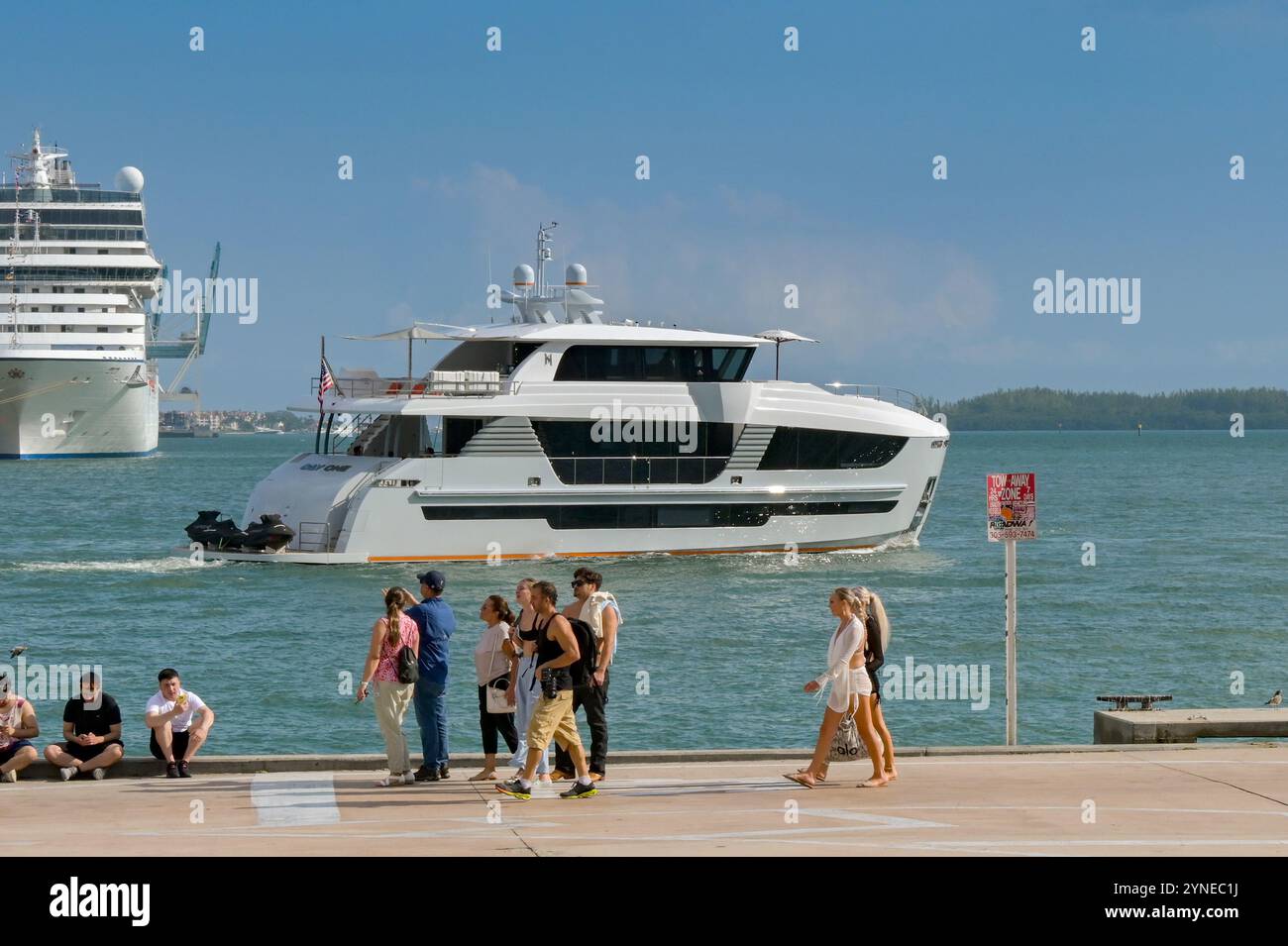 Miami, Florida, Stati Uniti - 3 dicembre 2023: Gruppo di persone che camminano lungo il lungomare di Miami con il lussuoso yacht Day One sullo sfondo Foto Stock