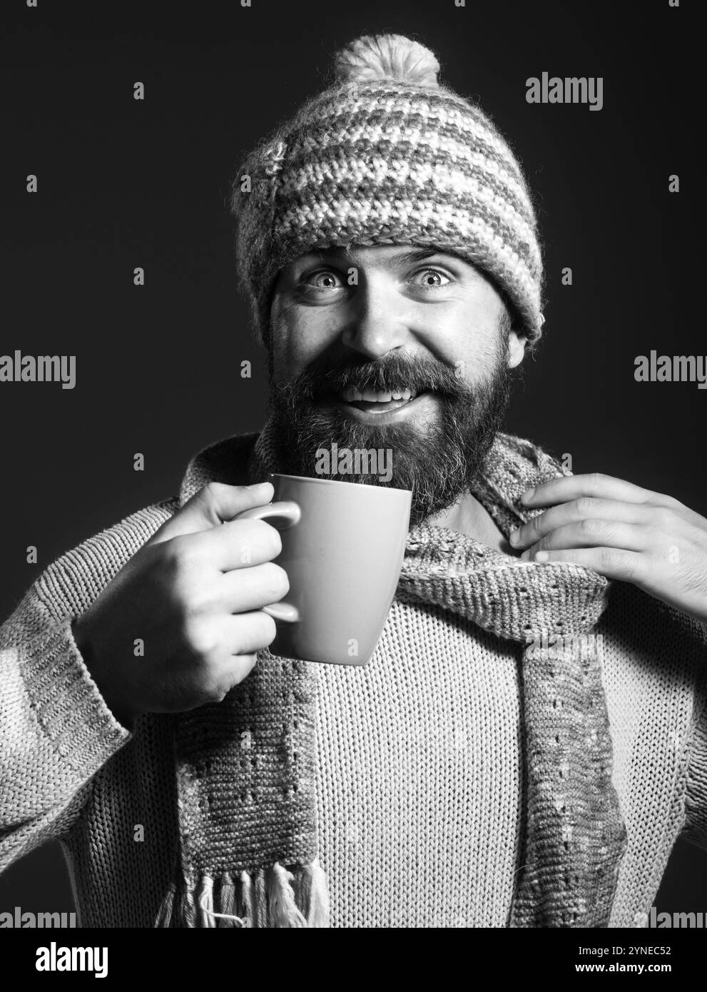 L'ora del caffè. Uomo con barba felice in un abbigliamento informale con una tazza di tè o caffè. Bell'uomo con barba e baffi in maglia, cappello e sciarpa Foto Stock