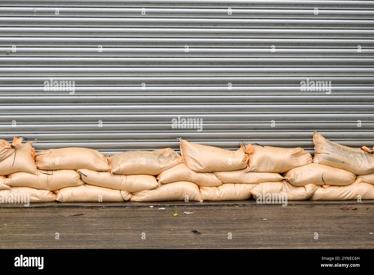 Sacchetti di sabbia impilati contro la porta a rulli di una fabbrica per evitare inondazioni dovute all'acqua inondabile in seguito a forti piogge provocate da una tempesta Foto Stock