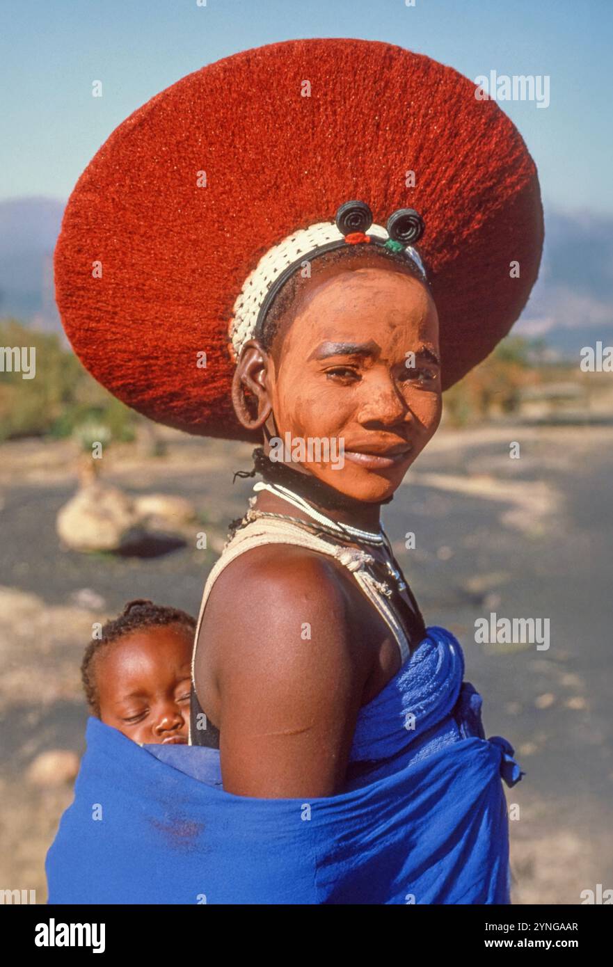 Ritratto di una bella donna Zulu, con il suo bambino, in abito tradizionale e con un cappello isicholo. Foto Stock