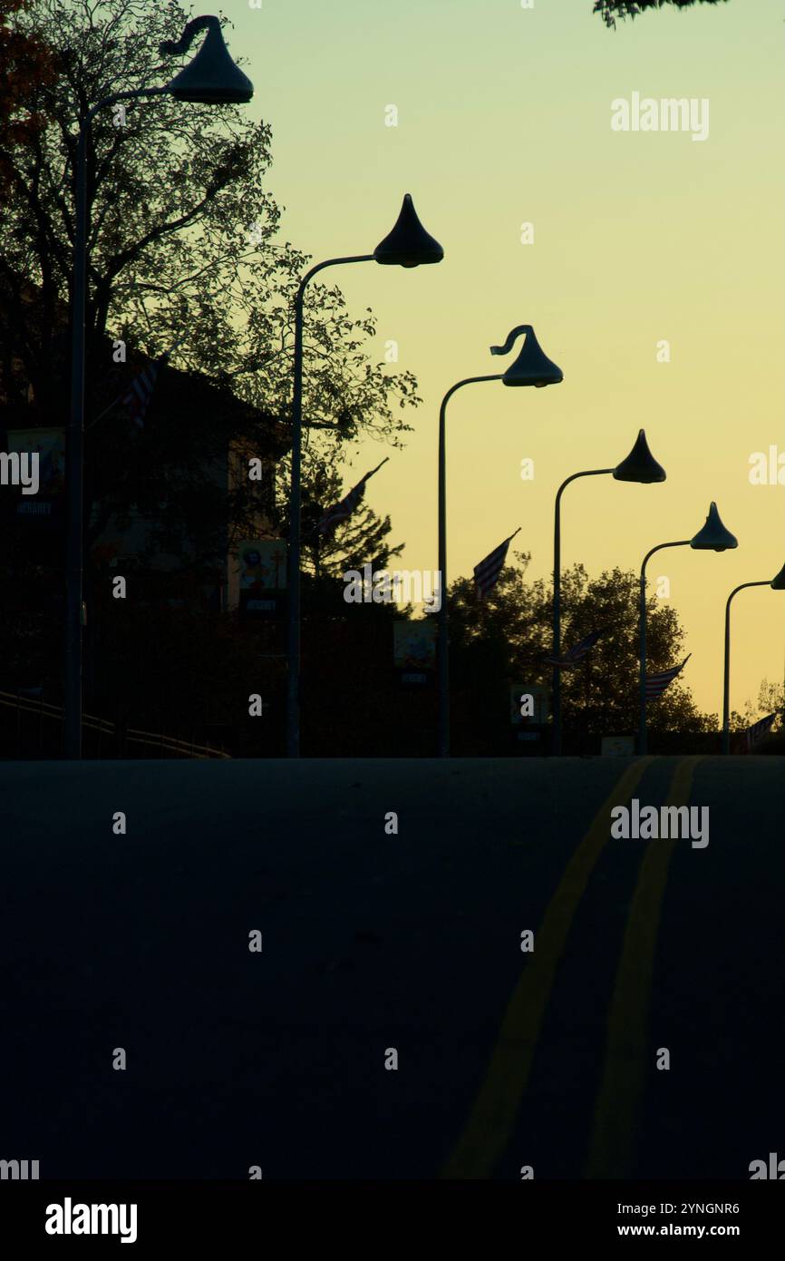 I lampioni a forma di Hershey Kiss sono sagomati dal sole che tramonta nel centro di Hershey, Pennsylvania, USA, lungo Chocolate Avenue al crepuscolo. Foto Stock