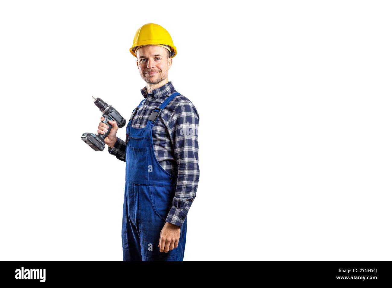 Costruttore sorridente con un elmetto che regge un avvitatore a batteria isolato su bianco Foto Stock