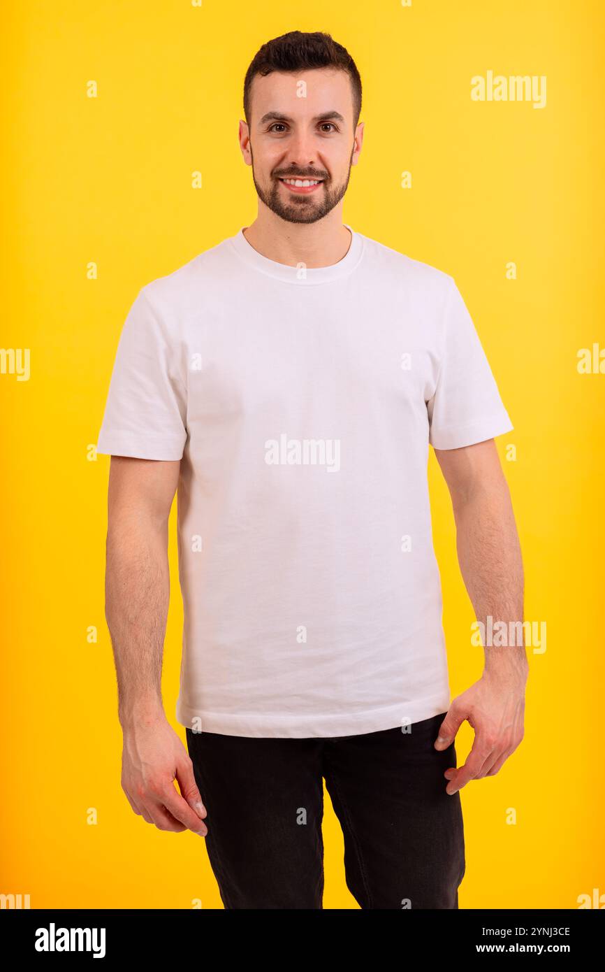 Ritratto di un uomo sorridente con t-shirt bianca su sfondo giallo. Verticale Foto Stock