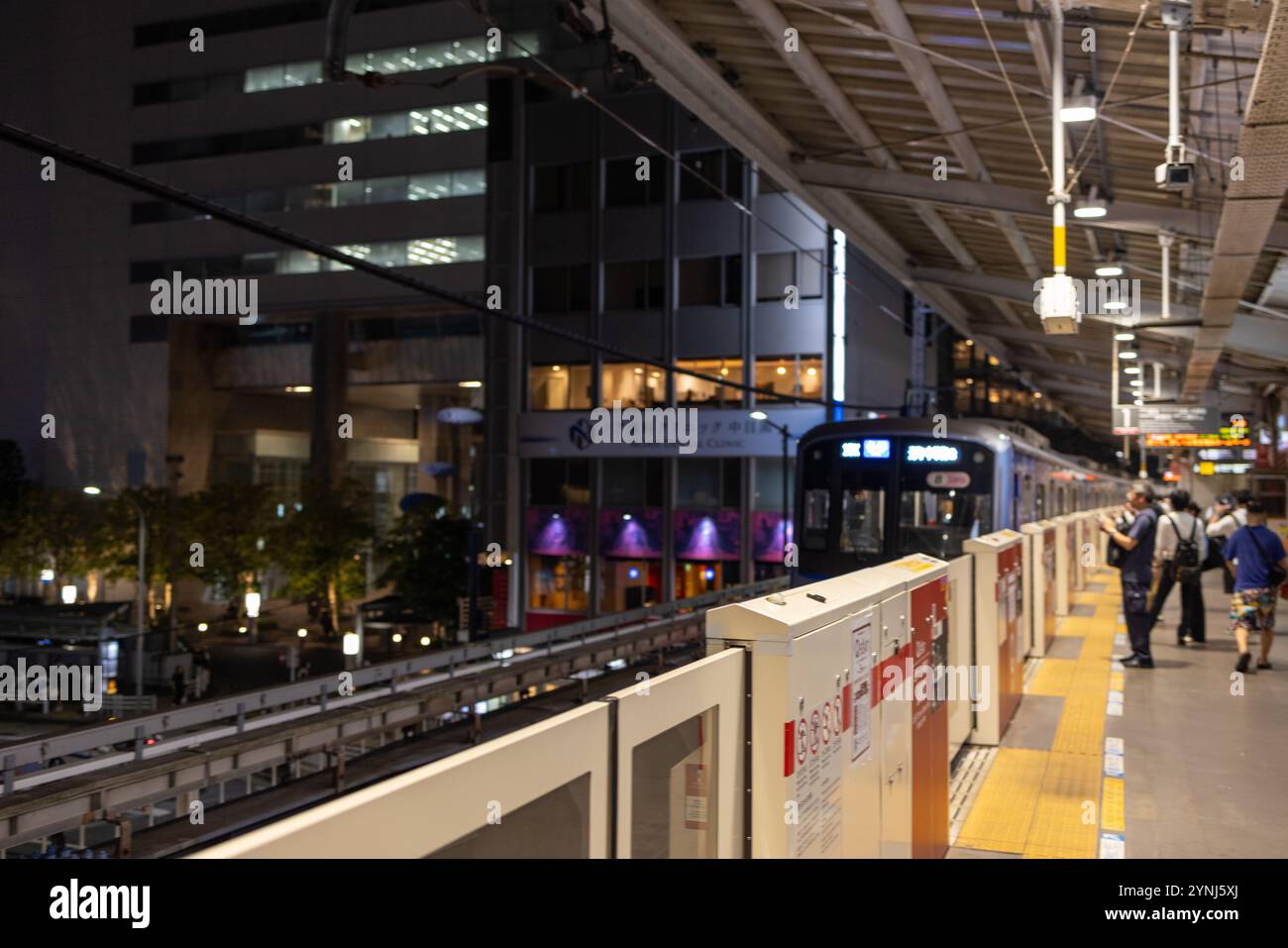 Stazione della metropolitana di Tokyo scena notturna con pendolari e arrivo in treno Foto Stock
