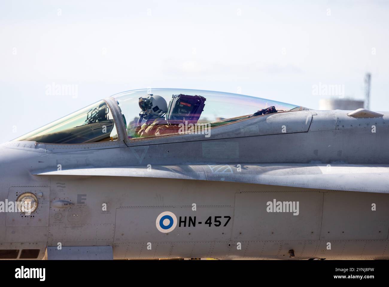 Un primo piano di un pilota di caccia seduto nella cabina di pilotaggio di un jet, catturato attraverso il tettuccio riflettente. Casco avanzato del pilota e tuta da volo emph Foto Stock