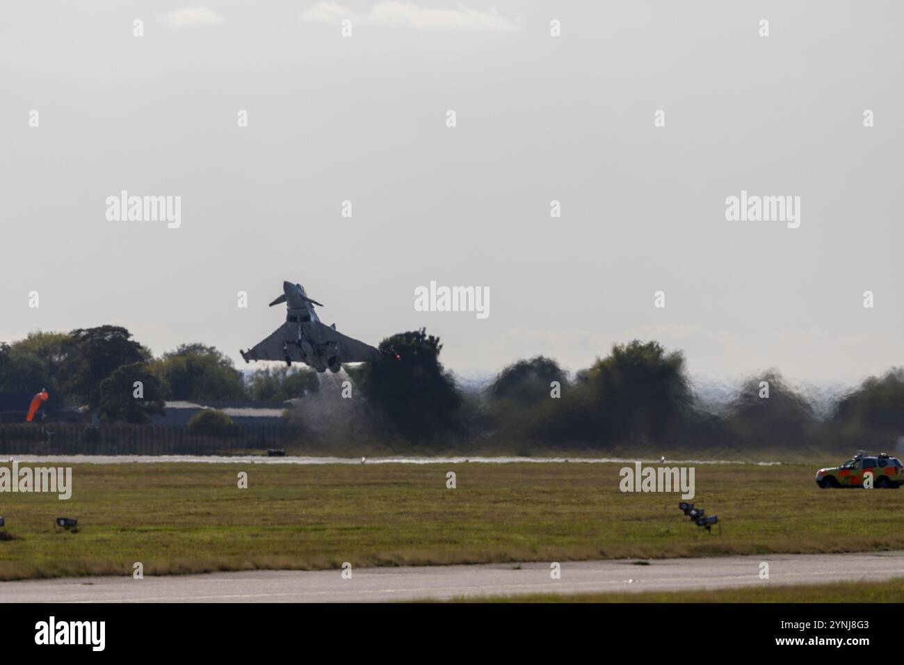 Un Eurofighter Typhoon esegue un decollo verticale spettacolare, mostrando la sua potenza e agilità. Sullo sfondo del campo d'aviazione, questo Highlig di scena Foto Stock