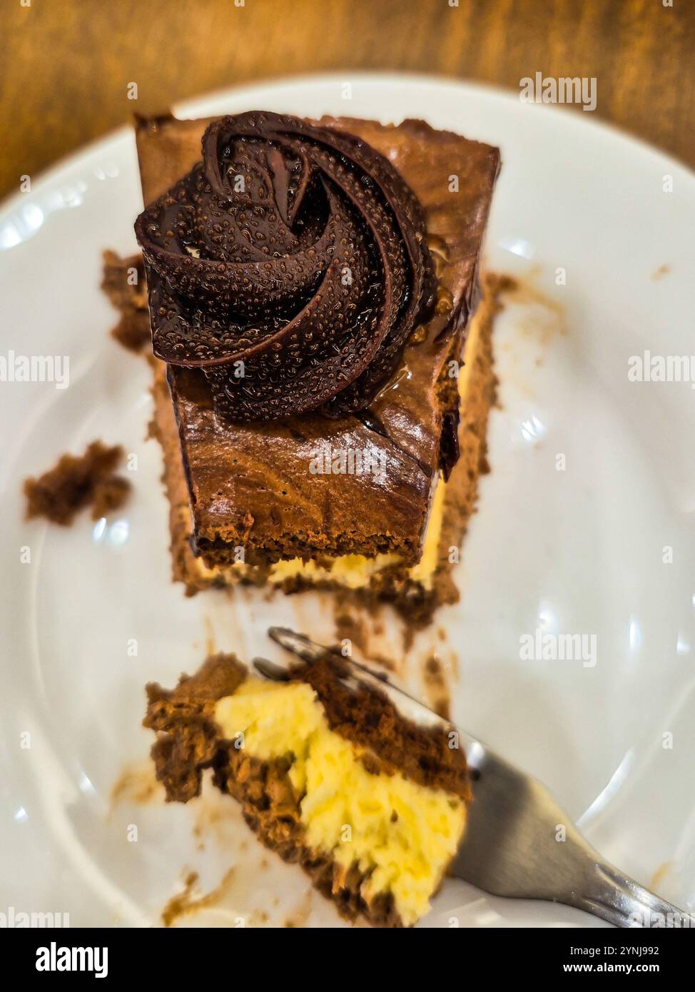 Goiania, Goias, Brasile – 25 novembre 2024: Un pezzo di torta al cioccolato con glassa, all'interno di un piatto di porcellana bianca. Una porzione della torta su una forchetta. - Immagine stock catturata con smartphone