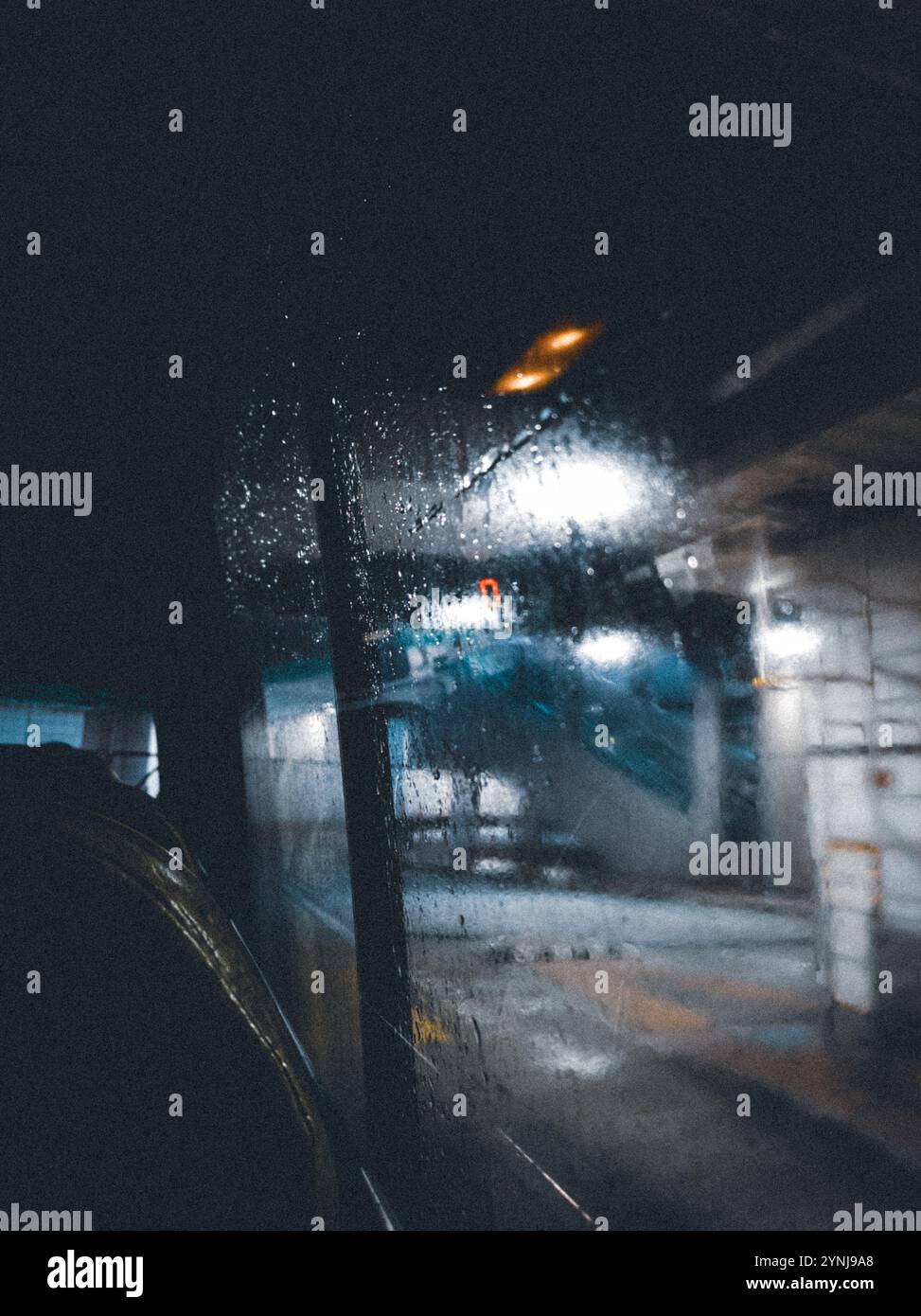 Ambientazione urbana in stile Moody vista dalla finestra a striature di pioggia di notte con luci e riflessi sfocati Foto Stock