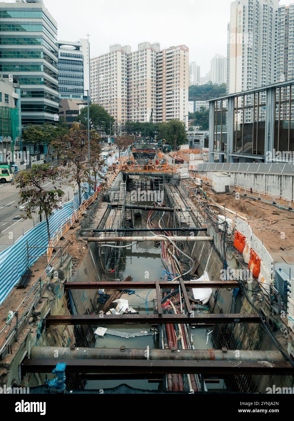 Cantiere urbano con tubi a vista, appartamenti alti ed edifici moderni che raffigurano lo sviluppo delle infrastrutture. Foto Stock
