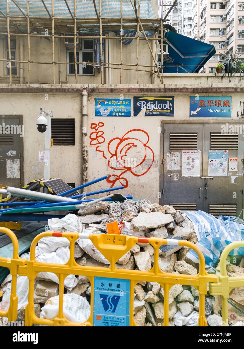 Urban Construction Site con coloratissimi graffiti, impalcature in bambù e macerie in una vivace scena di Hong Kong Street Foto Stock