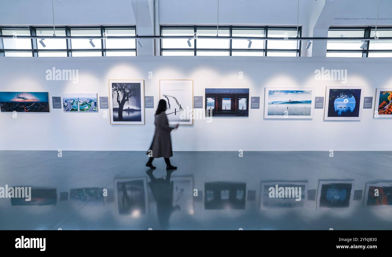 Hangzhou, la provincia cinese dello Zhejiang. 25 novembre 2024. Una donna visita una mostra fotografica a tema sul patrimonio mondiale della Cina a Hangzhou, nella provincia di Zhejiang, nella Cina orientale, 25 novembre 2024. La mostra che si tiene qui lunedì presenta i 59 siti cinesi che sono stati iscritti nella lista del patrimonio mondiale dell'UNESCO. Crediti: Xu Yu/Xinhua/Alamy Live News Foto Stock