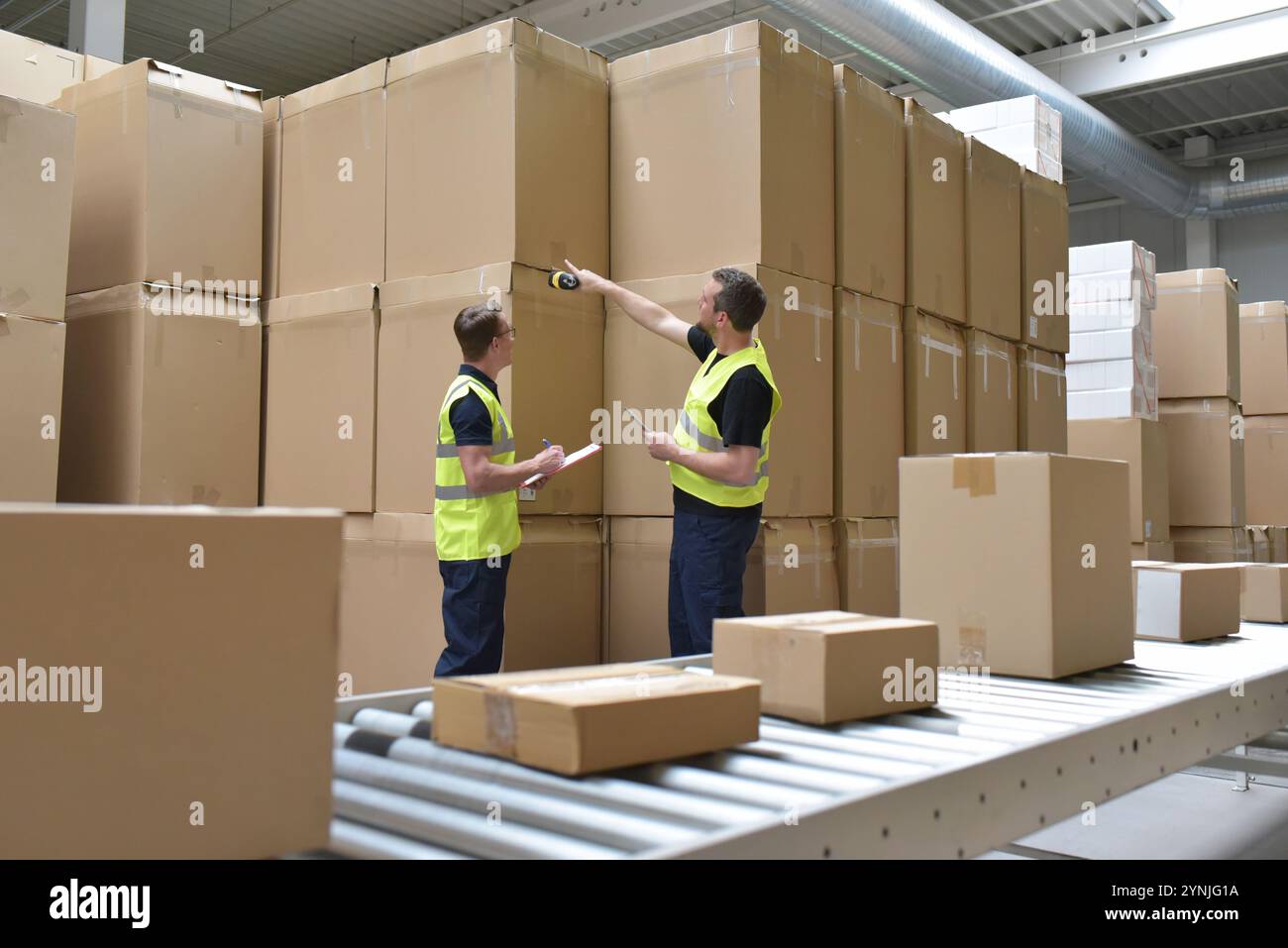 Lavoratore in un magazzino nel settore logistico lavorazione pacchi sulla linea di assemblaggio - trasporto ed elaborazione ordini in commercio Foto Stock